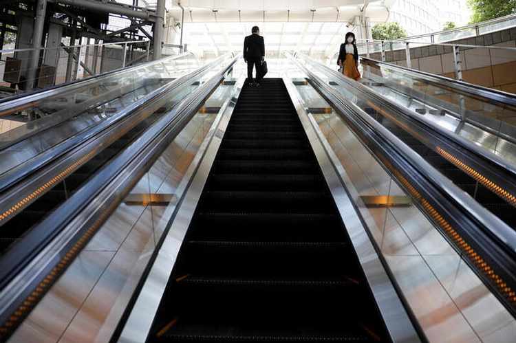 People wearing protective face masks use an escalator in a business building amid the coronavirus disease (COVID-19) outbreak in Tokyo, Japan, May 14, 2020. REUTERS/Kim Kyung-Hoon